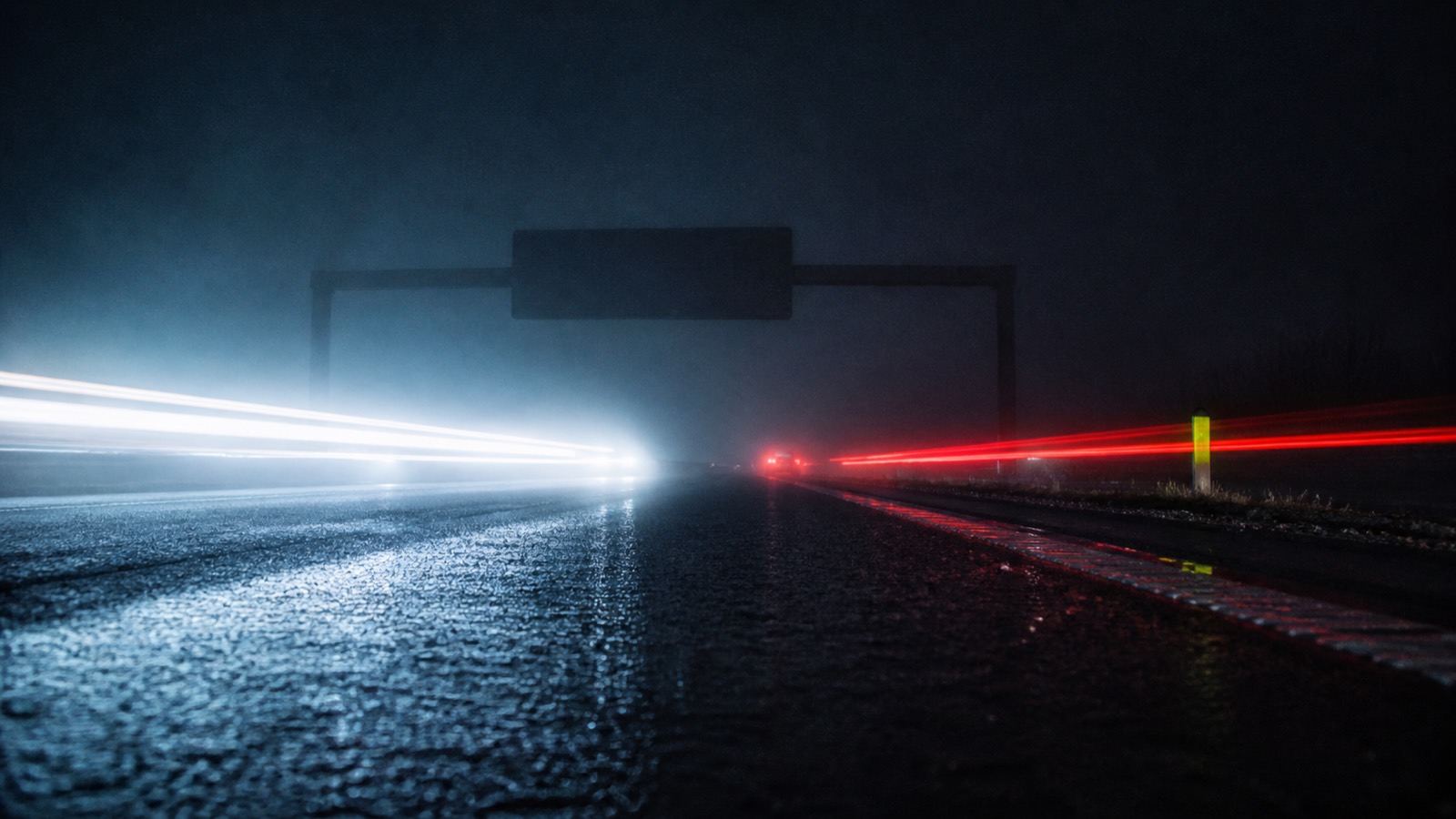 Motorway at night in fog, light trails of lorries running in both directions.